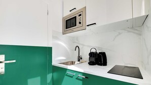 A compact kitchen with a built-in microwave, a sink, and a black countertop. - Cosy Cocoon for 2P with A/C - Near Montmartre (Paris)