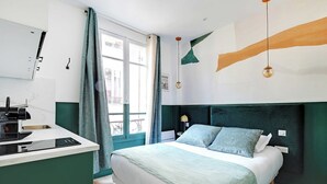 A modern bedroom with a bed, bedside table, and a window with curtains.