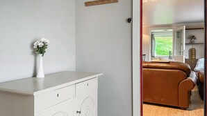 A modern room with a white dresser, a brown leather sofa, and a view of a garden through a window. - 2 bedroom lovely home in Færvik (Færvik)