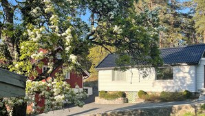 A small white house with a dark roof, surrounded by trees with white blossoms. - 2 bedroom lovely home in Færvik (Færvik)