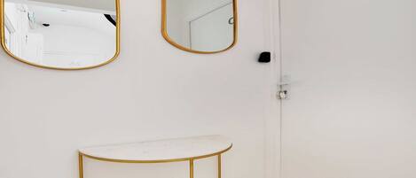 A white bathroom with two gold-framed mirrors, a white vanity, and a door labeled "2D".
