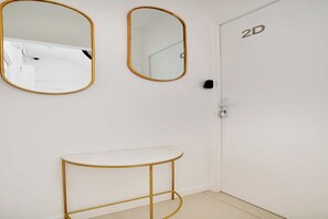 A modern bathroom with a white vanity, two wall-mounted mirrors, and a simple door.