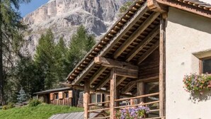 A rustic chalet with a wooden balcony, white walls, and flower boxes.