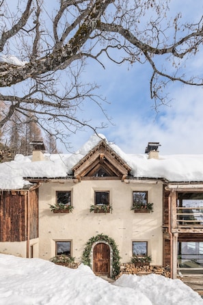 A chalet with a wooden facade, a snow-covered roof, and a wooden door.