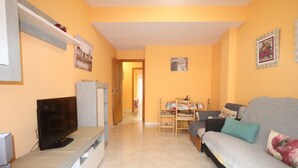 Una sala de estar con televisor, sofá y comedor con mesa y sillas.