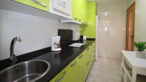 Una cocina con gabinetes verdes, un lavamanos de acero inoxidable, un microondas y una cafetera.