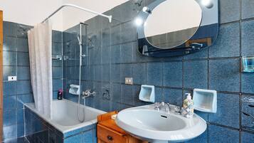 Une salle de bain avec une baignoire, un lavabo, un miroir et une douche.