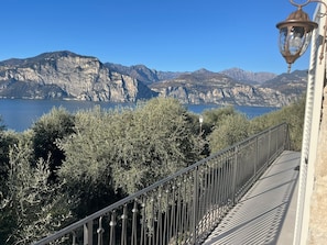 Vista costera con barandilla metálica, farola y montañas al fondo.