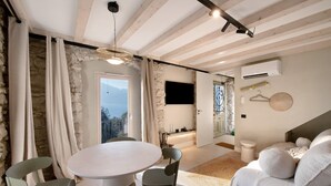 A modern interior with a stone wall, a round dining table, and a sofa with cushions. - Apartment Oliva (45 m2) with shared terrace, sauna and lake view (Brenzone sul Garda)