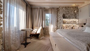 A bedroom with a stone wall, a bed, a small table, and a chair. - Apartment Oliva (45 m2) with shared terrace, sauna and lake view (Brenzone sul Garda)
