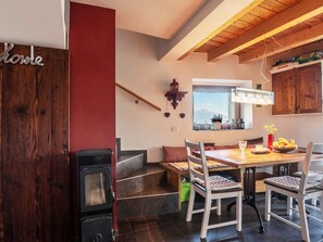 Une cuisine chaleureuse avec un plafond en bois, un poêle et une table à manger entourée de chaises.