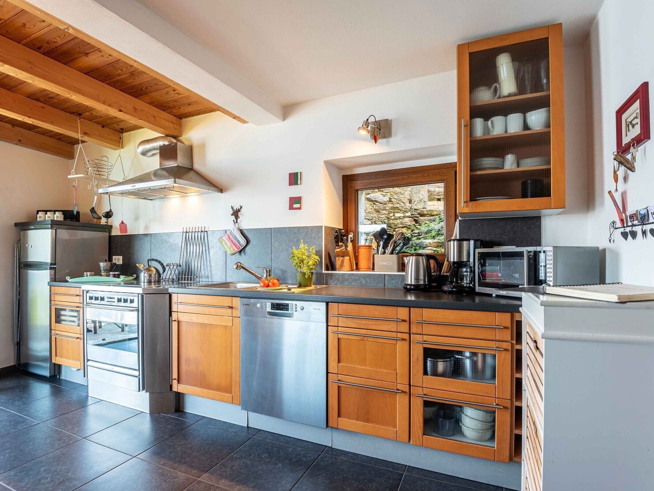 Une cuisine moderne avec des meubles en bois, des appareils électroménagers en acier inoxydable et un pare-feu en pierre.