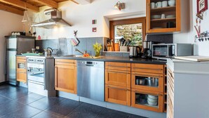 A modern kitchen with wooden cabinets, stainless steel appliances, and a stone backsplash. - Holiday Home 'Casa Bianca' with Lake View, Private Terrace and Wi-Fi (Saliana (Pianello del Lario))