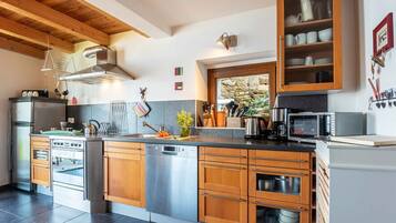 Une cuisine moderne avec des meubles en bois, des appareils électroménagers en acier inoxydable et un pare-feu en pierre.