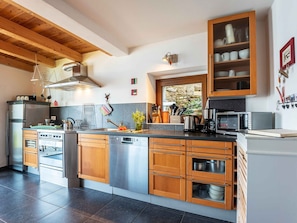 Une cuisine moderne avec des meubles en bois, des appareils électroménagers en acier inoxydable et un pare-feu en pierre.