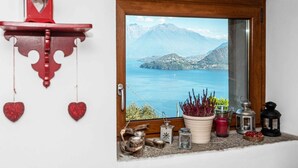 A window with a view of a lake and mountains, a red lantern, and various decorative items on the windowsill. - Holiday Home 'Casa Bianca' with Lake View, Private Terrace and Wi-Fi (Saliana (Pianello del Lario))