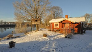 Un chalet rustique au bord d’un lac, avec une structure en bois et une maison rouge.