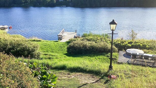 Une vue sur le lac, avec un quai en bois, un lampadaire et un petit bateau.