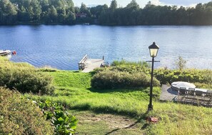 Une vue sur le lac, avec un quai en bois, un lampadaire et un petit bateau.