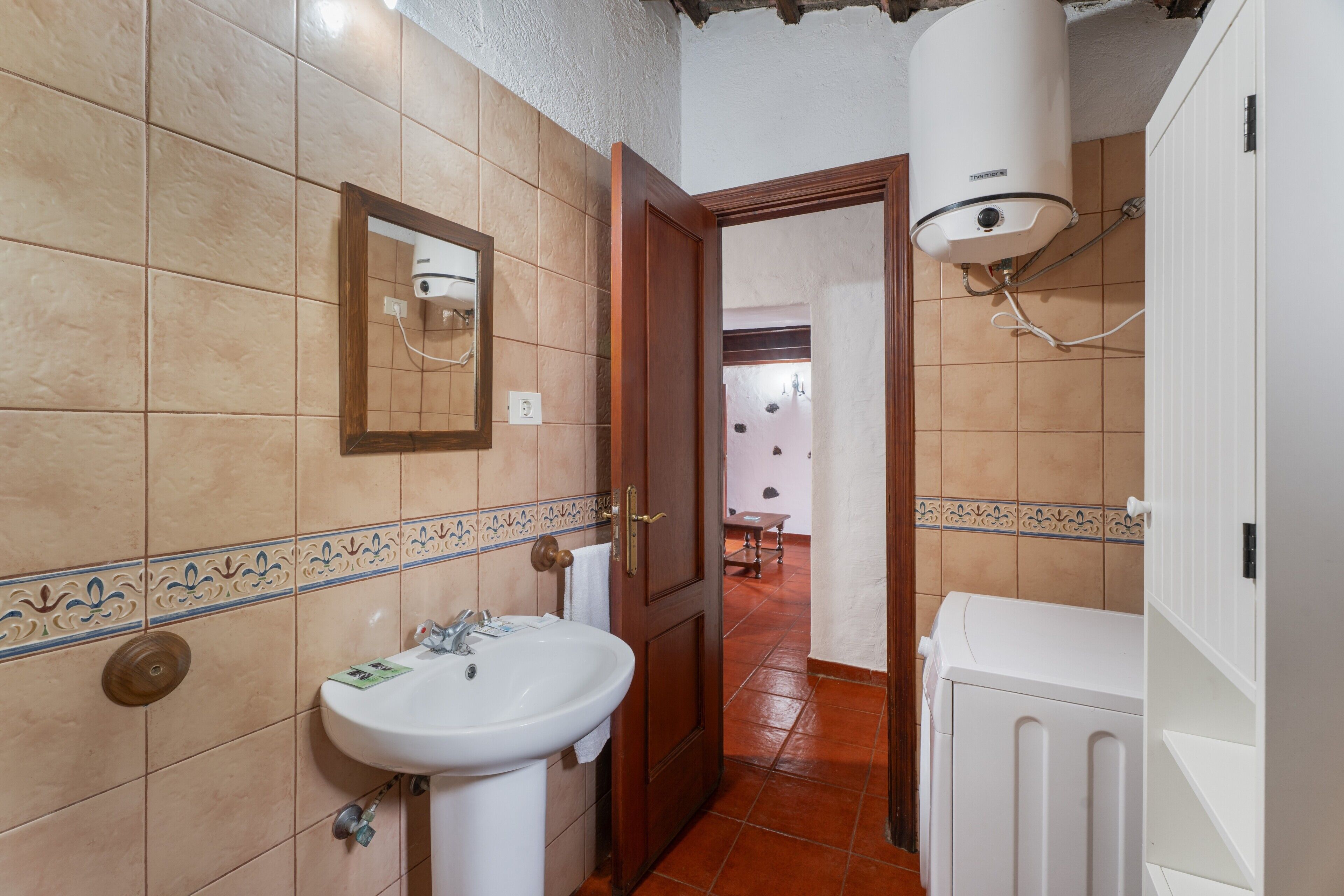 Un baño con lavabo, espejo y radiador blanco.