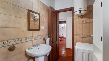 Un baño con lavabo, espejo y radiador blanco.