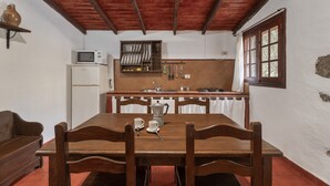 Een eethoek met een houten tafel, stoelen, een magnetron en een wastafel.