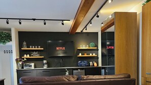 Une chambre moderne avec un grand lit, un coin cuisine équipé d’une télévision et un plafond en bois.