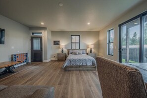 A bedroom with a bed, bedside tables, a bench, and a large window.
