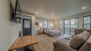 Une chambre spacieuse comprenant un lit, des tables de chevet, un banc en bois et un canapé.