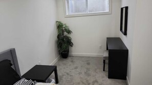 Relax in this cozy space with a sofa, side table, and storage unit, surrounded by a lush potted plant.