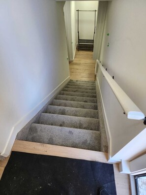 Stairs lead to an upper floor, flanked by plain walls and a handrail.