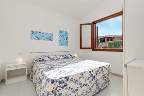 A bedroom with a bed, bedside tables, and a window with a view of a building. - Holiday Home 'Villetta A 800mt Dall'Isuledda' with Shared Terrace (san teodoro)
