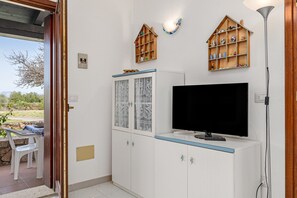 A room with a television, cabinets, a table with chairs, and a view of the outdoors. - Holiday Home 'Villetta A 800mt Dall'Isuledda' with Shared Terrace (san teodoro)