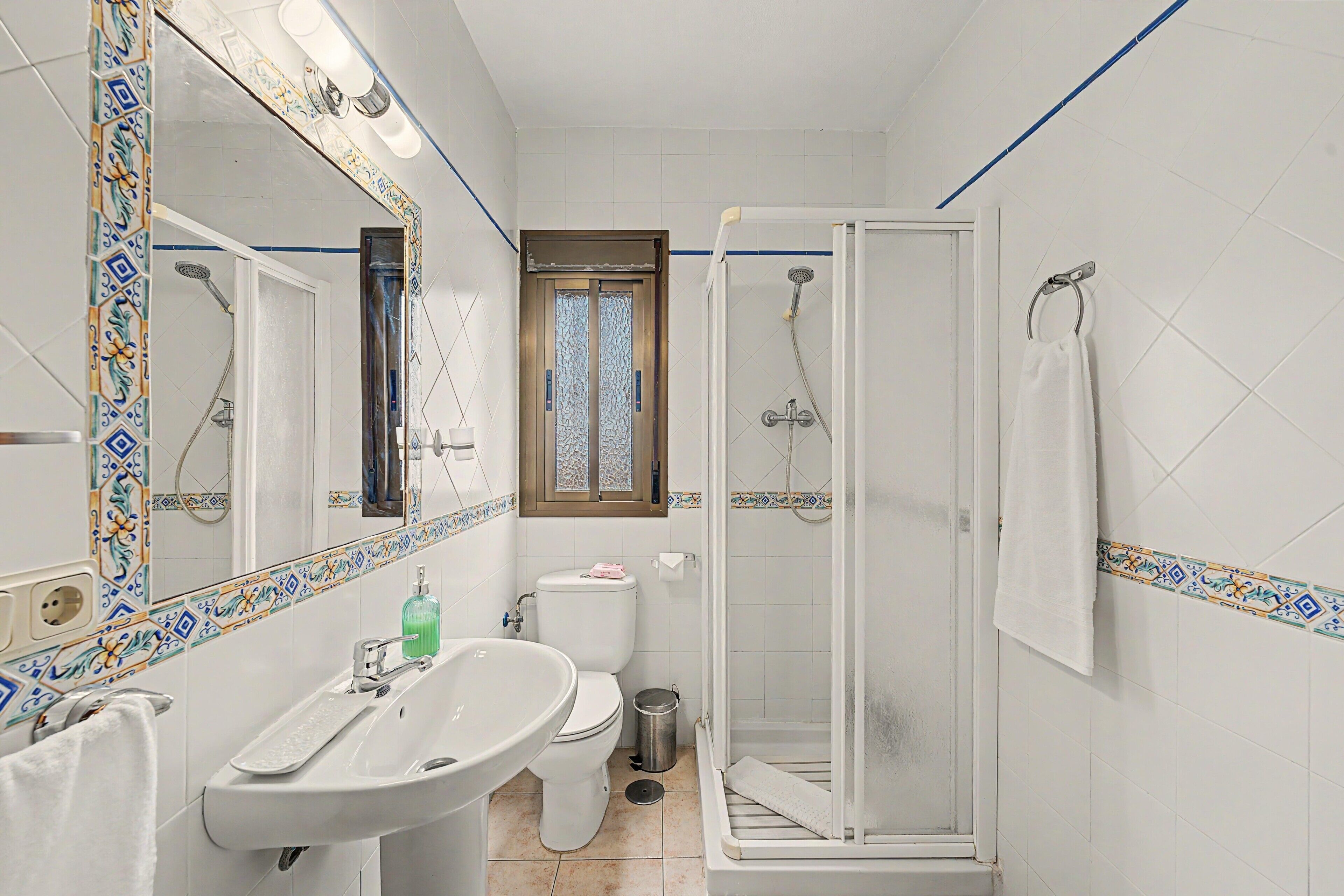 A bathroom with a white sink, toilet, and shower enclosure.