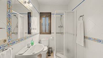 A bathroom with a white sink, toilet, and shower enclosure.