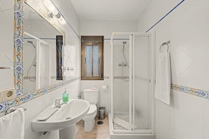 Een badkamer met een wit wastafelmeubel, toilet en douchecabine.