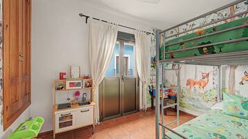 Een kinderkamer met stapelbedden, een bureau en een raam met gordijnen.