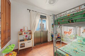 A child's bedroom with bunk beds, a desk, and a window with curtains.
