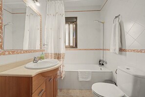 A bathroom with a bathtub, toilet, sink, and a mirror.