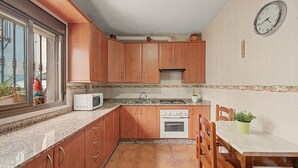 Une cuisine avec des meubles de rangement en bois, un four à micro-ondes, un évier et une cuisinière.