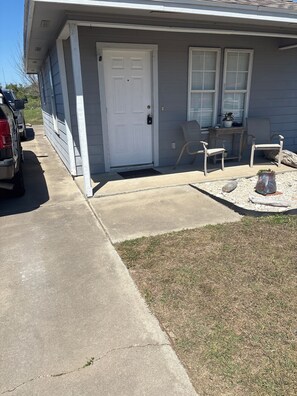 A residential house with a front door, two windows, a small porch, and a concrete driveway. - PRIME LOCATION IMAGES OF PLACES NOT REACHABLE. NOT COZY BUT IT WORKS (Corpus Christi)