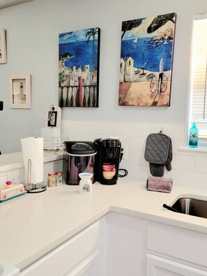 A kitchen with white cabinets, a coffee maker, a kettle, and two paintings on the wall. - PRIME LOCATION LOCATED BETWEEN CITY AND THE BEACH (Corpus Christi)