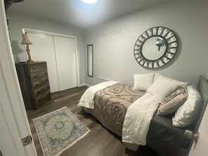 A bedroom with a bed, dresser, mirror, and a rug. - PRIME LOCATION LOCATED BETWEEN CITY AND THE BEACH (Corpus Christi)