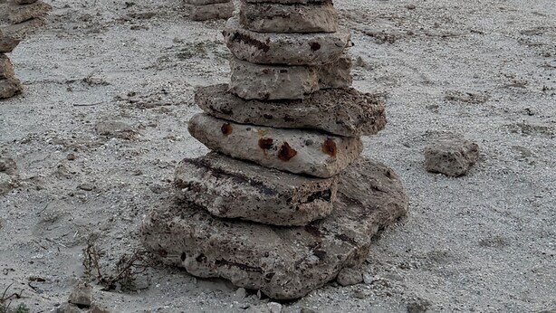 Ein Steinhaufen an einem Strand bei Sonnenuntergang.