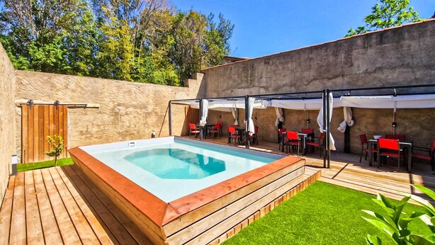 Una bañera de hidromasaje rectangular con un muelle de madera y una zona verde al frente.