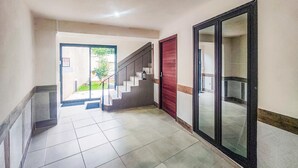 Un pasillo con piso de baldosas, una escalera y una puerta roja.