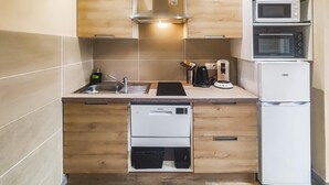 Cocina compacta con horno empotrado, microondas y lavavajillas.
