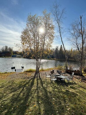 A lakeside setting with a dock, a picnic table, and chairs. - 2-Story Lakeside Oasis w/ Private Dock, Kayaks (Wasilla)