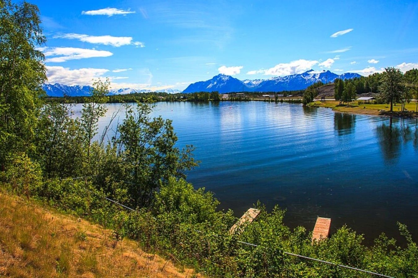 Un lac bordé de montagnes, entouré de verdure et sous un ciel dégagé.