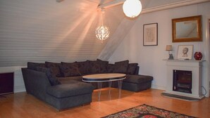 A cozy living room with a sectional sofa, a round coffee table, and a fireplace.